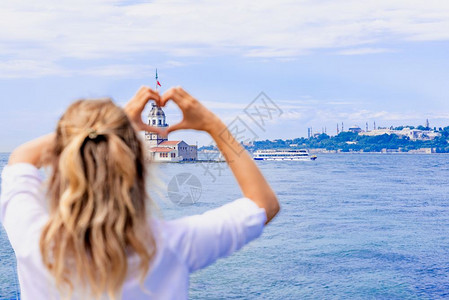 旅行者心美丽的女旅行者在土耳其伊斯坦布尔的一个受欢迎目地MaidensTower的风景上手牵造心形背景