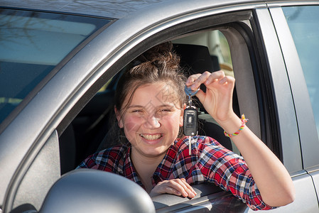 年轻快乐的少女孩坐在车里展示钥匙女性的高清图片素材