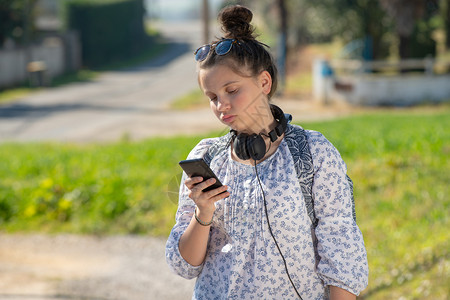 一名年轻少女等待校车并使用智能手机图片