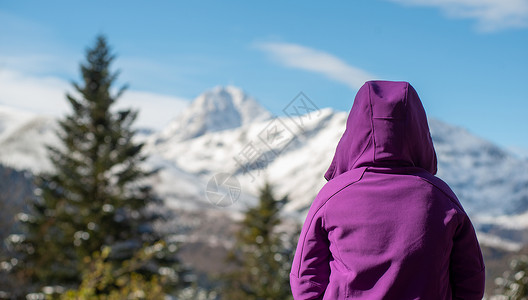 雪帽山一个穿紫色衣服的女人看着雪山背景