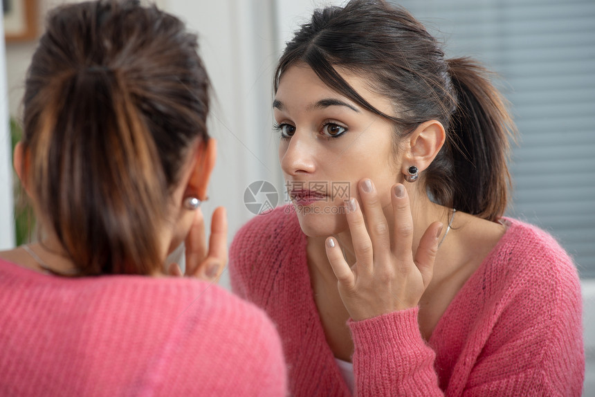 一个美丽的年轻黑发女人看着镜子中的自己图片