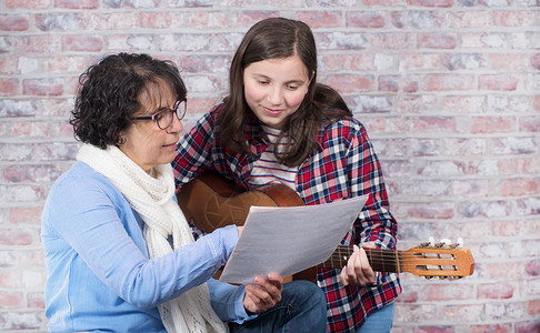 一个年轻的少女与老师一起学习弹吉他音乐高清图片素材