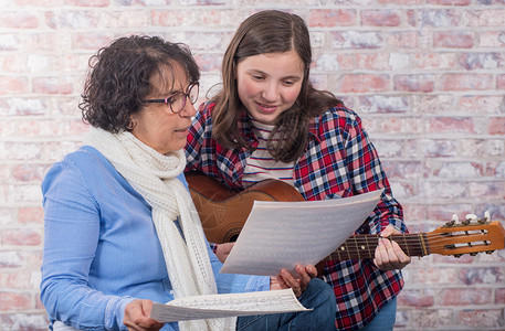 一个年轻的少女与老师一起学习弹吉他课程高清图片素材