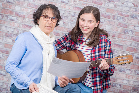 一个年轻的少女与老师一起学习弹吉他工具高清图片素材
