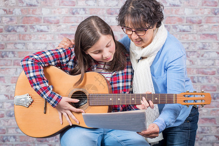 一个年轻的少女与老师一起学习弹吉他教育高清图片素材