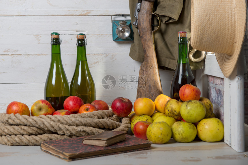 木制桌上含有黄苹果和红的酒瓶图片