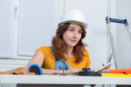 年轻笑着的女建筑师办公室里戴头盔的女建筑师图片