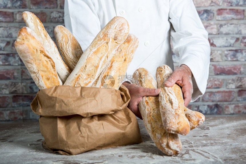 a面包师持有传统法国面包图片