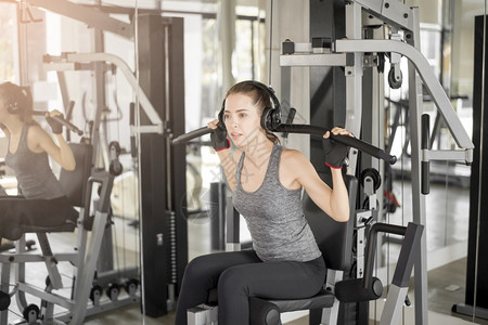 漂亮的年轻运动女子带着耳机在健身房健身图片