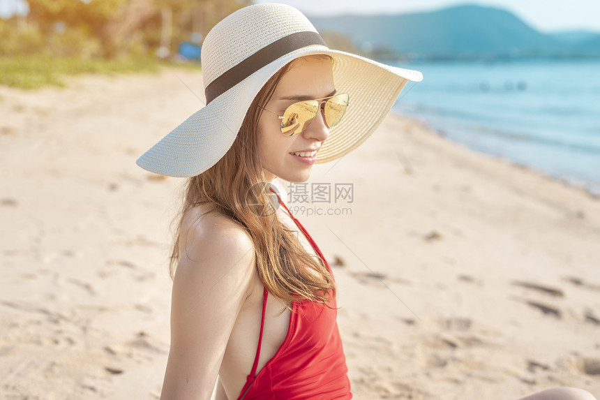 穿红泳衣的美女坐在沙滩上图片