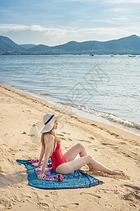 红色泳装穿红泳衣的美女坐在沙滩上背景