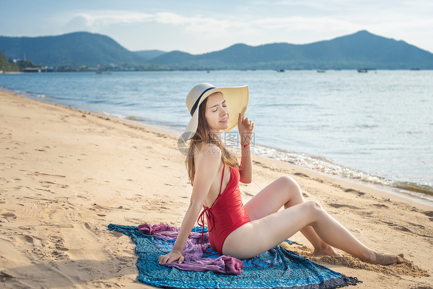 穿红泳衣的美女坐在沙滩上图片