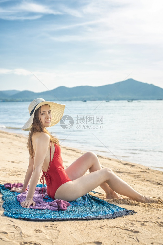 穿红泳衣的美女坐在沙滩上图片