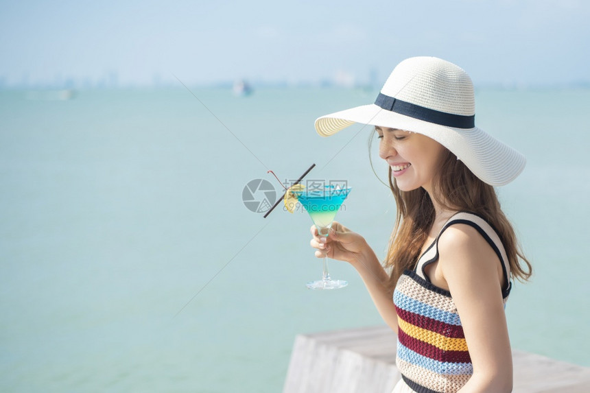 美丽的女人正在海滩喝冰水夏天在海滩喝水夏天的概念图片