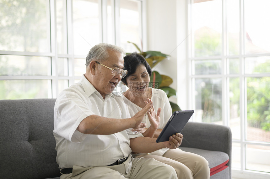一个亚洲快乐的老年人正在用视频打电话在家里放松微笑健康的老年退休祖父母老年技术概念一个亚洲快乐的老年人正在用视频打电话微笑健康的图片