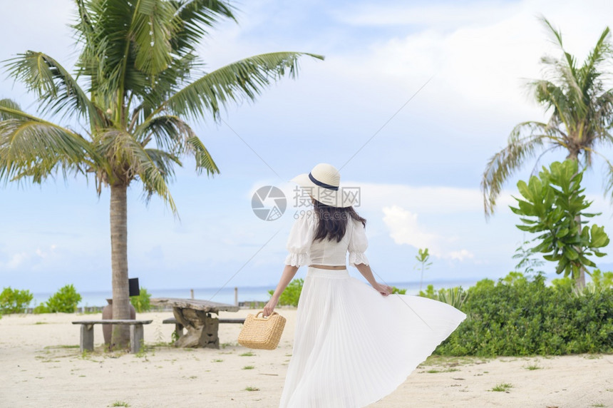 一个穿着白裙子的快乐美丽女人在海滩夏天和节假日享受放松图片