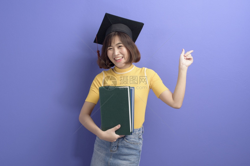 短发女青年带着毕业帽手上抱着书图片