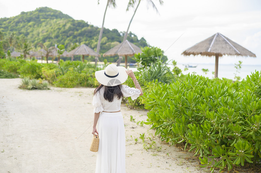 一个穿着白裙子的快乐美丽女人在海滩夏天和节假日享受放松图片