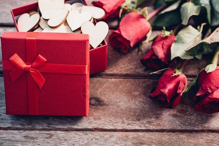花玫瑰和红礼盒放在木背景上情人节概念图片