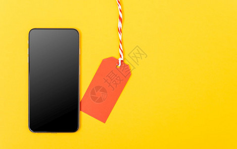 网上购物空白红色标签和黄背景的智能手机空白屏幕并有供使用的复制空间图片