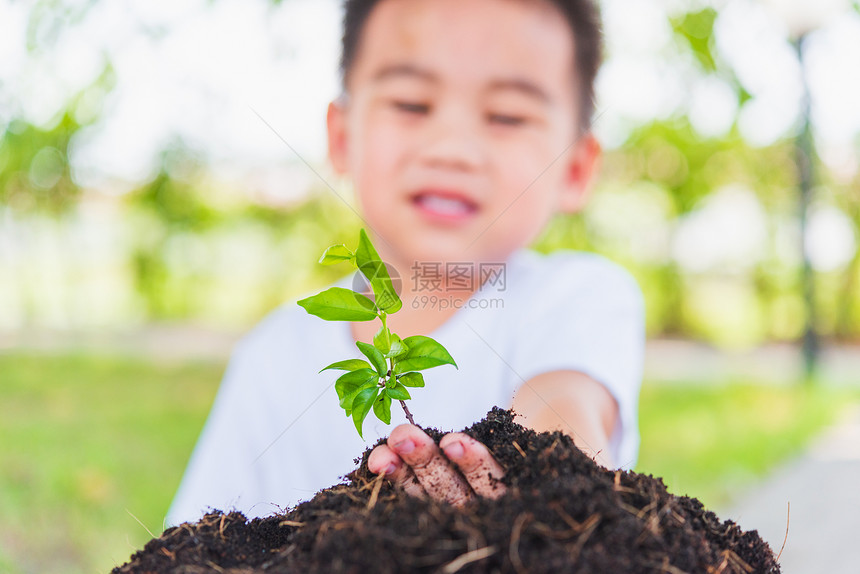 世界环境日概念亚洲可爱的小快乐男孩手在绿花园背景的黑土上种植小树图片