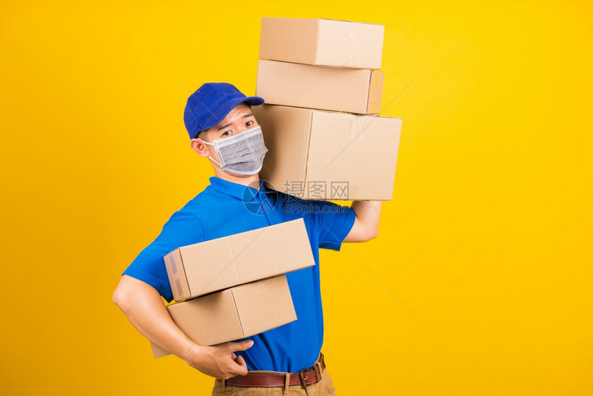 身穿蓝色T恤衫和制服的亚洲年轻送货工人身穿蓝色T恤衫和帽子制服的亚洲年轻送货员身着面罩在冠状或COVID19下身穿面罩背着保护式图片