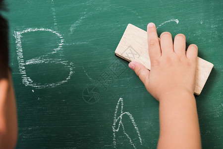 后亚洲可爱小男孩幼稚儿园校服擦干净或黑粉绿色学校板上用海绵擦粉第一次到学校教育概念背景