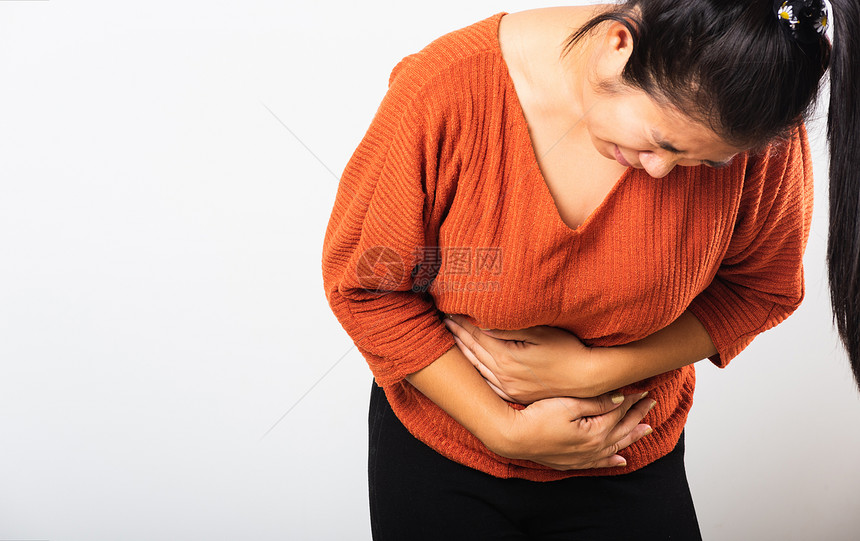 她生病的亚裔妇女有胃痛肚子手握在腹部身体的一分女有痛苦的胃腹部发炎或慢胃工作室被孤立在白色背景上图片