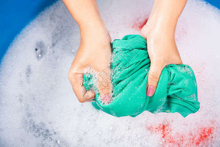 气泡清洁紧闭的亚洲年轻女在盆地用手洗彩衣物女用洗涤剂挤的湿布有水中肥皂泡工作室拍摄背景洗衣概念背景