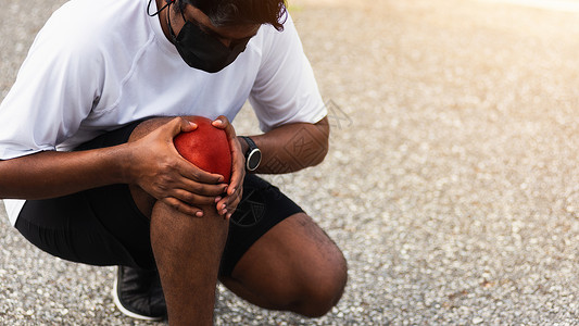 因表不凡在户外街头健康公园跑动时黑人男子戴着手表握着膝盖疼痛身体运动因锻炼概念而受伤背景