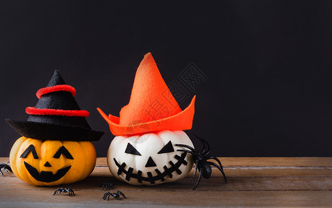 黑背景南瓜有趣的万圣节派对概念鬼南瓜的头灯插惊吓的笑脸戴着帽子和蜘蛛在木桌黑背景上背景
