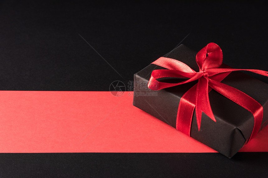 黑色星期五销售购物和拳击日概念包装黑纸的礼品盒和红领带物色和黑背景的拍摄室图片