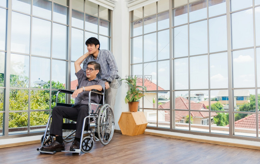 坐在轮椅上的亚洲残疾老年与办公室的团队讨论互动图片