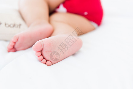 暖脚宝美丽的亚洲新生儿小宝在家中睡白床上快乐宝穿着红衬衫在房间里放松枕头背景
