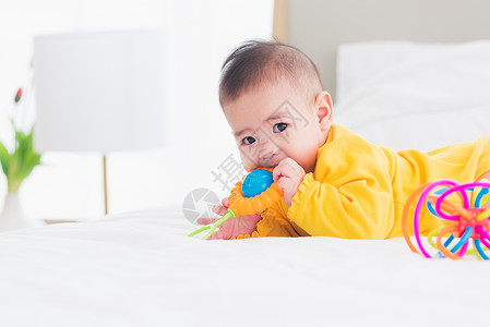 美丽的年轻亚洲新生儿小宝在家中的床上笑快乐的婴儿微穿着黄色衬衫在房间里放松蹒跚学步的孩子高清图片素材
