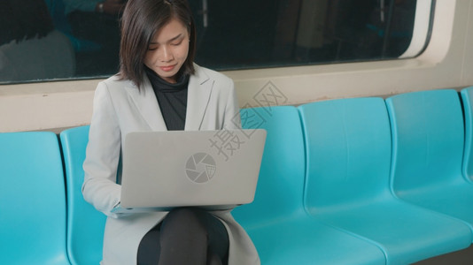 亚洲青年商业女在上班时使用笔记本电脑在地铁火车上工作图片