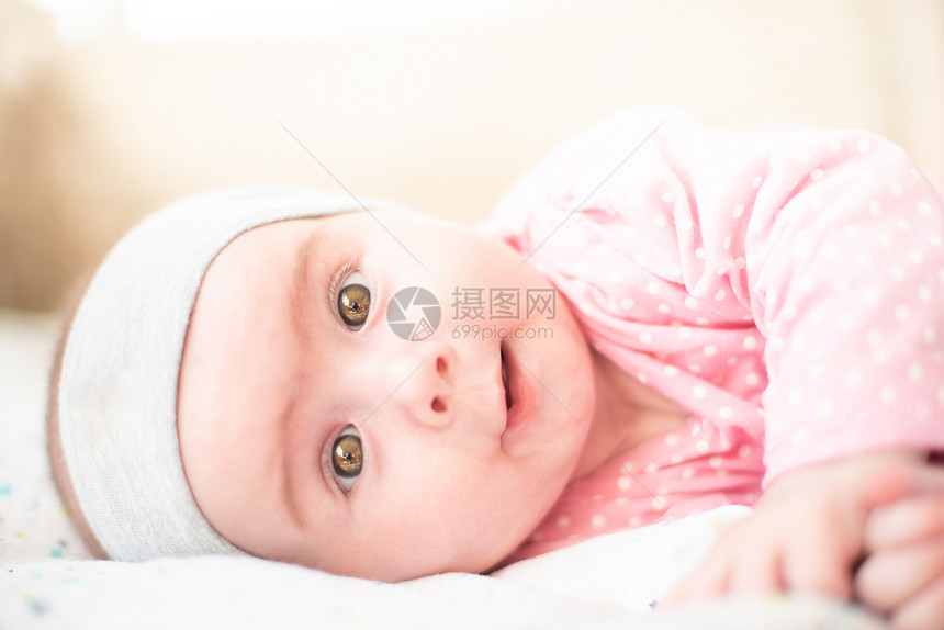 可爱的粉红色女婴躺在一旁面带微笑地看着镜头复制顶部空间6个月大的婴儿可爱的粉红色女婴躺在一旁面带微笑地看着镜头健康观图片