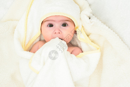 6个月大的婴儿睡在肚子上的床头抬起用大眼睛看相机自然卧室灯光6个月大的婴儿睡在肚子上的床用大眼睛看相机自然光背景图片