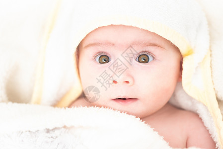 洗澡后被用毛巾的可爱女婴、用棕色大眼睛向上看、复制空间洗澡的概念6个月婴儿用毛巾包着的可爱女婴、复制背景