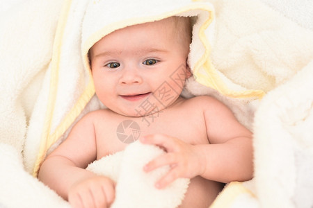 6个月大的婴儿睡在肚子上的床头抬起用大眼睛看相机自然卧室灯光6个月大的婴儿睡在肚子上的床用大眼睛看相机自然光背景图片
