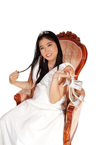 一位美丽的年轻新娘坐在旧时装椅子上穿着白色衣服的穿着高跟鞋图片