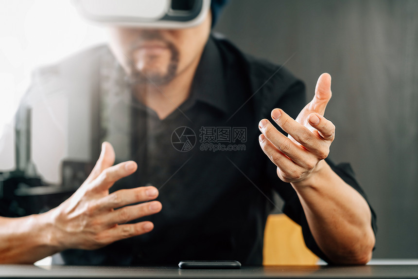 商人在现代办公室佩戴虚拟现实护目镜用手机VR头戴VR盔图片