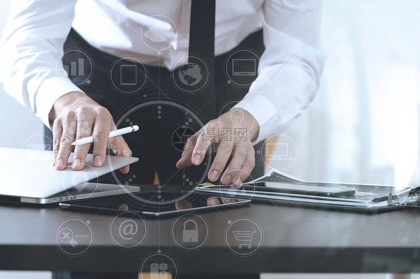 在现代办公室木制桌上用智能电话数字平板脑和笔记本与虚拟图标图片