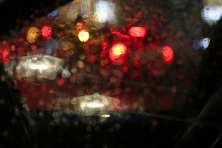 夜晚大城市的灯光穿过车玻璃上面满是雨滴模糊的抽象背景图片