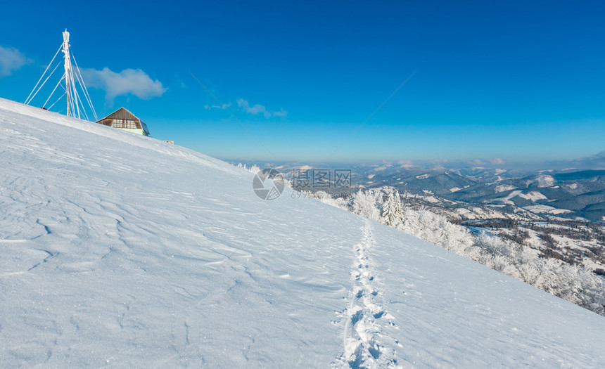 美丽的冬季红霜树通讯塔和人行道穿过蓝天空背景的山坡上雪田喀尔巴阡山乌克兰图片