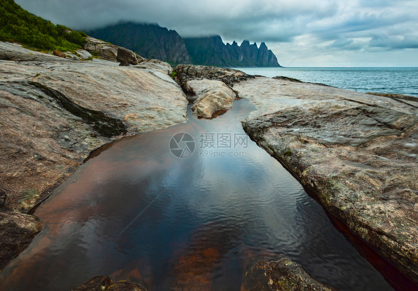 挪威Senja市Ersfjord的沙滩上有潮汐浴夏季极地日夜海岸远处的龙牙岩图片