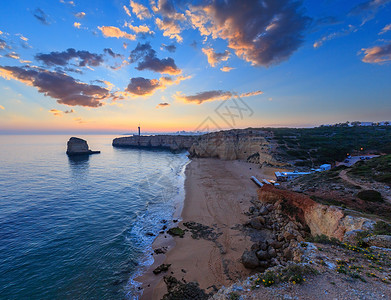 海边的日落景色与本塔多祭坛灯塔普拉亚达阿富拉达海滩西景费拉古多拉戈亚阿尔加维葡萄牙背景图片