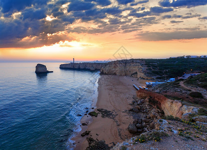 海边的日落景色与本塔多祭坛灯塔普拉亚达阿富拉达海滩西景费拉古多拉戈亚阿尔加维葡萄牙背景图片