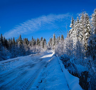 通往边远山区小村庄高的二级公路穿过雪林流和路边的木栅栏背景图片