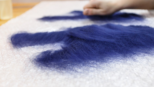 使用湿感觉工艺蓝色梅里诺羊毛用手套制纤维层覆盖了关闭的切割模式图片